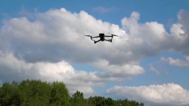İnsansız hava aracı bulutların arka planında asılı, pervaneler dönüyor. Hava keşfi kavramı, hava fotoğrafçılığı, yukarıdan gelen hava gözlemi.