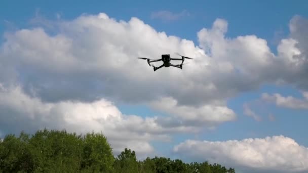 无人机在云彩的背景下悬挂在天空中 叶片在旋转 空中侦察 航空摄影 空中观察的概念 — 图库视频影像