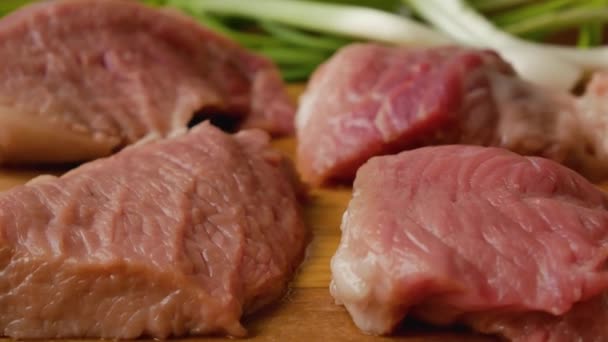Stücke Rohes Schweinefleisch Auf Einem Hölzernen Küchenbrett Hintergrund Grüne Zwiebelfedern — Stockvideo