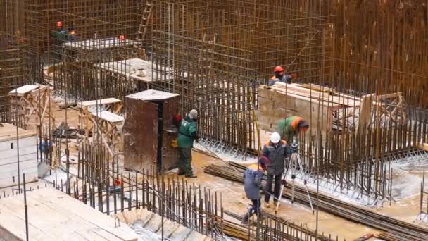 哈尔科夫 乌克兰 2023年12月4日 建筑工地上戴头盔和制服的工人 它们携带金属钢筋 并为未来的混凝土墙奠定基础 一个工人和一个 — 图库视频影像