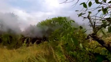 Çalılıklardan bir tank ateş ediyor. Gerçek bir savaş. Rus-Ukrayna savaşı.