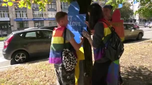 ウクライナのハリコフ 2023 虹色のベストの若者は 碑文Ltt愛のルールを持つ人々のボール紙のシルエットを木に取り付けます プライド Lgbt コミュニティ — ストック動画