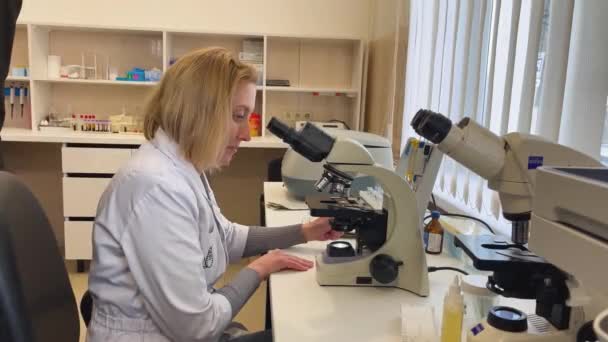乌克兰哈尔科夫 2024年2月1日 一位身穿白衣的生物学家通过显微镜进行了一项研究 — 图库视频影像