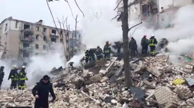 Kharkiv, Ukrayna - 23 Ocak 2024: Kurtarma ekipleri, Ukrayna 'nın bir kentindeki çok katlı bir binanın çökmüş girişinin yanındaki enkaz yığınının üzerinde duruyor. Füze saldırısının sonuçları