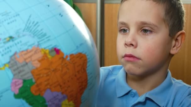 Ένα Αγόρι Ετών Περιστρέφεται Και Εξετάζει Μια Υδρόγειο Σφαίρα Διδάσκω — Αρχείο Βίντεο