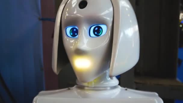 白いプラスチック製のヒューマノイドロボットが曲がり 頭を回し ライトを点滅させる 人間のアシスタントとしての人工知能 ロボコンサルタント — ストック動画