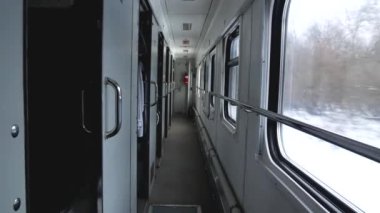 Tren vagonu içeride. Kompartımanın kapıları görünür durumda. Pencereden geçen bir kış manzarası görebilirsiniz. Kışın trenle seyahat et..