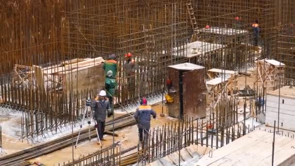 哈尔科夫 乌克兰 2023年12月4日 一个大型建筑工地上的建筑商 工人们搬运钢筋 为混凝土墙做地基 旁边是一个带测距仪的工程师 盖房子 — 图库视频影像