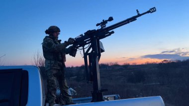 Kharkiv, Ukraine - February, 27, 2024: A soldier stands in the back of a pickup truck and controls a heavy machine gun. A mobile fire group shoots down an unmanned aerial vehicle, a drone, and a clipart