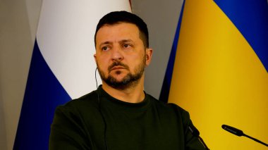 Kharkiv, Ukrayna - Mart 01, 2024: Ukrayna Cumhurbaşkanı Volodymyr Zelensky mikrofon önünde Ukrayna ulusal bayrağının arka planına tepki olarak dinliyor ve başını sallıyor.