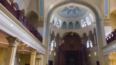 Sinagog binası içeriden. Kubbeli tavanı olan iki katlı bir salon. Güneş ışınları birçok pencereden girer. Yahudi duaları için dini bir bina..