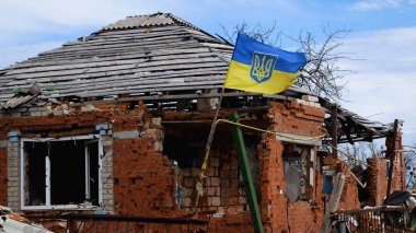 Bir Ukrayna sarı ve mavi bayrağı yıkılmış bir evin üzerinde dalgalanıyor. Rus-Ukrayna savaşı.