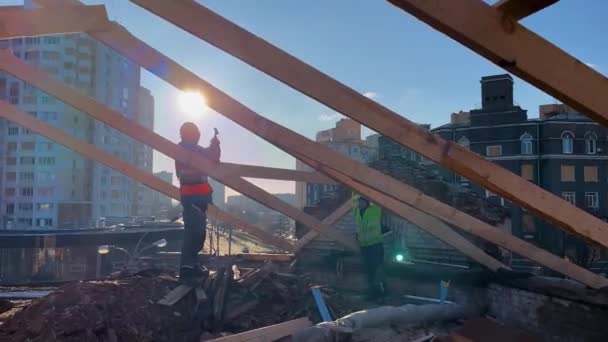 ウクライナのハリコフ 2023年11月30日 労働者が建物の屋根を修理する 彼はハンマーでハンターにぶつかった 家の屋根に建設工事を行いました 背景にはマルチストアがあります — ストック動画