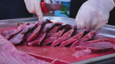 Aşçının eldivenli elleri bir bıçakla balığı kesti. Aşçı filetoyu parçalara ayırır ve kenara koyar. Taze deniz ürünleri hazırlığı.