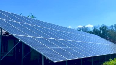 Yere mavi gökyüzüne karşı büyük güneş panelleri kurulur. Arka planda ağaçlar var. Panorama. Güneş enerjisi kavramı, yeşil enerji, alternatif enerji türleri..