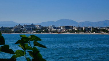 Deniz, ufukta çok katlı binaları ve otelleri olan büyük bir Akdeniz kenti görebilirsiniz. Dağların arkasında. Turizm ve yaz tatili tatil beldesi konsepti.