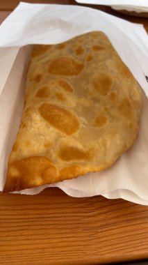 Büyük, iştah açıcı sıcak bir cheburek masanın üzerinde beyaz bir kese kağıdının içinde yatıyor. El çantayı açar. Atıştırmalık..