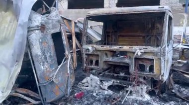 Kırık bir binanın arka planında yanmış kamyonlar. Füze saldırısından sonra. Rus-Ukrayna savaşı.