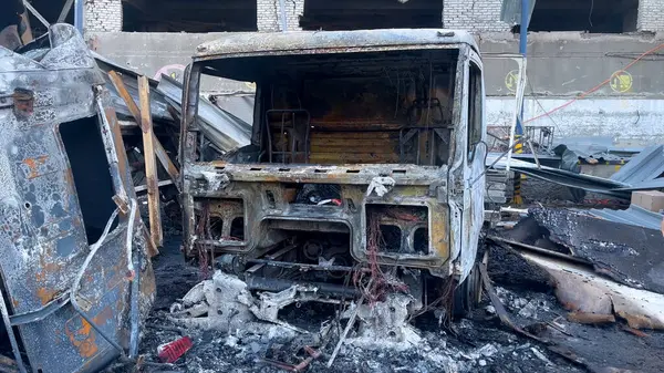 stock image Burnt-out trucks against the background of a broken building. Aftermath of the missile strike. Russian-Ukrainian war.