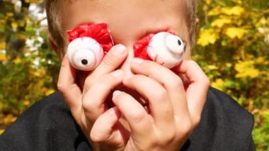 Cadılar Bayramı kostümü giymiş bir çocuk ölü bir adamın korkunç plastik gözlerini gözlerine koyar ve etrafındaki insanları korkutur. Cadılar Bayramı 'nı kutluyor.