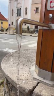 İçme suyu, antik bir Avrupa şehrinin sokaklarındaki bir musluktan akar..