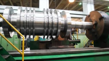 Fabrika atölyesindeki bir makinede büyük bir metal parçası dönüyor. Büyük ölçekli endüstriyel üretim. Metal parçalarının işlenmesi.