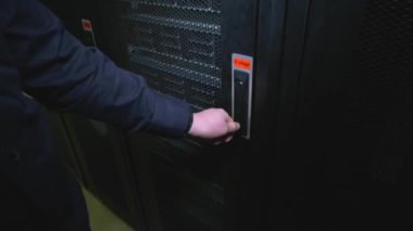 Bir adamın eli sunucu dolabının kapısını açar. Sunucu görünür durumda. Güçlü sunucularda veri depolama kavramı. Bilgi toplama, işleme ve depolama.
