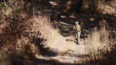 Kharkiv, Ukrayna - 27 Ekim 2024: Askeri üniformalı askerler ellerinde makineli tüfeklerle orman yolunda yürüyorlar. Gerçek bir savaş. Askeri tatbikatlar. Russo-Ukrayna savaşı.