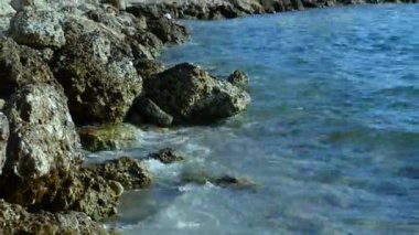 Deniz dalgaları Akdeniz 'in sıcak denizinin kıyılarında taşları yıkar. Issız bir plajda dinlenmek. Denize seyahatler.