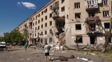 Kharkiv, Ukrayna - 23 Haziran 2024: Hava bombası ve füze saldırısından sonra bir ev yıkıldı. Evin duvarları, pencereleri yok. İnsanlar evin yanında yürür. Kurtarma işlemi.