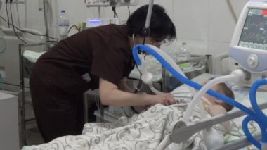 Kharkiv, Ukrayna - 28 Haziran 2022: Doktor çocuğu hastanenin yoğun bakım ünitesinde muayene ediyor. Bebek solunum cihazına bağlı. Ölümcül derecede hasta olan çocukların hayatlarını kurtarıyorum.
