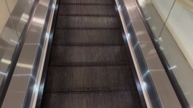 Alışveriş merkezindeki yürüyen merdiven kayışı yukarı çıkıyor ve çıkış kapısına gidiyor..