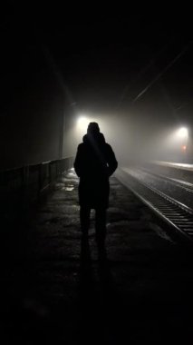 Sisteki fenerlerin altında demir raylar boyunca yürüyen bir kadın figürü. Depresyon, yalnızlık, kendini keşfetme kavramı..