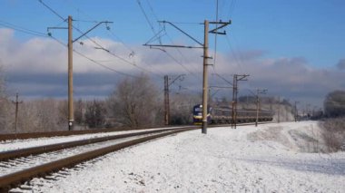 Kharkiv, Ukrayna - Ocak 05, 2025: Açık bir kış gününde bir banliyö treni karlı bir kırsalda seyahat eder. Ön manzara. Düşük ihtimal. Yolcu taşımacılığı. Tren yolculuğu..