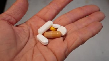 Bir kadın, tabletleri açık bir avuç içinde, yuvarlak ve kapsüllerde tutar. Tedavi konsepti, doktorun reçetesi, haplar. Kendi kendine tedavi, beslenme takviyeleri..