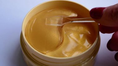 Bir kadın eli, cam bir çubukla paketten yüz derisi için jel yamaları alır. Yüz bakımı konsepti, evdeki kozmetik prosedürler. Gözlerinin altındaki deriye dikkat et. Yüze karşı savaş