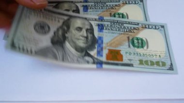 Tanınmayan kadınların elleri masaya yüz dolarlık banknotlar serer. Finans, ev ekonomisi, kazanç, maaş, kâr kavramı. Ev bütçesi. Para birimi aktarımları