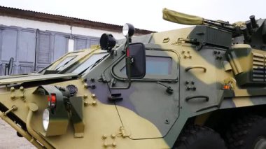 Askeri teçhizatlı bir hangarın arka planına karşı zırhlı bir personel taşıyıcısı. Panorama. Gerçek bir savaş sırasında zırhlı araçlar. Zırhlı arazi araçları olan off-road araçları. Russo.