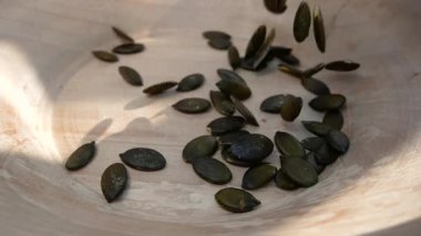 Balkabağı tohumları ahşap bir tabağa dökülür. Besleyici bir süper yiyecek olarak kabak tohumları. Sağlıklı atıştırmalıklar. Sağlıklı bir diyette besin kaynağı.