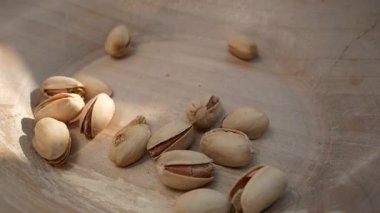 Fıstıklar ahşap bir tabağa düşer. Fıstıklı, besleyici bir süper yiyecek. Sağlıklı atıştırmalıklar. Sağlıklı bir diyette besin kaynağı.