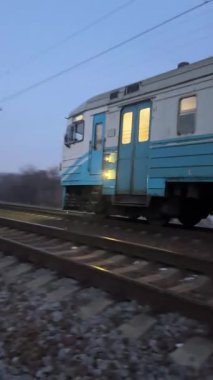 Kharkiv, Ukrayna - Marsh, 17, 2025: Akşam banliyö treni demiryolu ile gider. Pencerelerde ışıklar parlıyor. Yolcuların demiryolu ile taşınması. Demiryolu ile seyahat et.