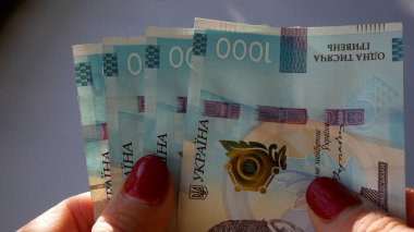 Kadınların elinde 1000 Hryvnia değerinde banknotlar var. Ukrayna para birimi. Bütçe kavramı, yükselen enflasyon, yükselen fiyatlar.
