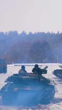 Kharkiv, Ukraine - January, 31, 2022: A tank with tankers on armor leaves the hangar and goes to combat positions. On the right is a column of tanks and armored personnel carriers. Russian-Ukrainian