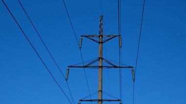 Bir elektrik hattının direği ve kabloları gökyüzünün arka planına karşı. Elektrik üretimi ve iletimi. Güç şebekelerinde bir kaza. Kesinti.
