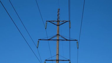 Bir elektrik hattının direği ve kabloları gökyüzünün arka planına karşı. Elektrik üretimi ve iletimi. Güç şebekelerinde bir kaza. Kesinti.