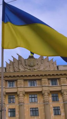 Ukrayna 'nın büyük sarı-mavi bayrağı Ukrayna' nın bir kentindeki idari bir binanın arka planında dalgalanır. Bağımsız Ukrayna devletinin bir sembolü olarak Ukrayna bayrağı