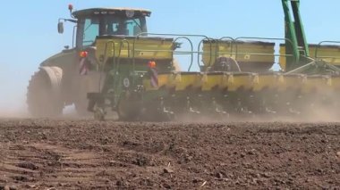 Tohum ekiciyle donatılmış traktör tarladan geçer, buğday ve ayçiçeği tohumları eker. Bahar ekimi kampanyası. Tarımsal ekinler ve kırsal mevsimsel işler yetiştirme kavramı.