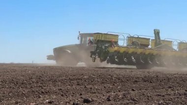 Tohum ekiciyle donatılmış traktör ilkbaharda döner, tarladan geçer, buğday ve ayçiçeği tohumları eker. Bahar ekimi kampanyası. Tarımsal ekinler ve kırsal mevsimler yetiştirme kavramı