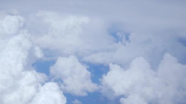 Beyaz pofuduk bulutlar açık mavi gökyüzünde, üst manzara, uçak penceresinden. Sakin havanın ve atmosferik güzelliğin hava manzarası.