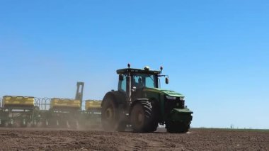 Kharkiv, Ukrayna - 17 Mayıs 2025: Tohum ekicilerle donatılmış traktör tarlada buğday ve ayçekirdeği ekiyor. Bahar ekimi kampanyası. Tarım ürünleri ve kırsal alanlarda yetişme kavramı